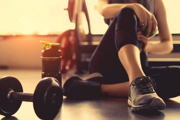 Sportlich aktive Frau mit Hanteln und Trinkflasche – bereit zur Regeneration nach dem Training