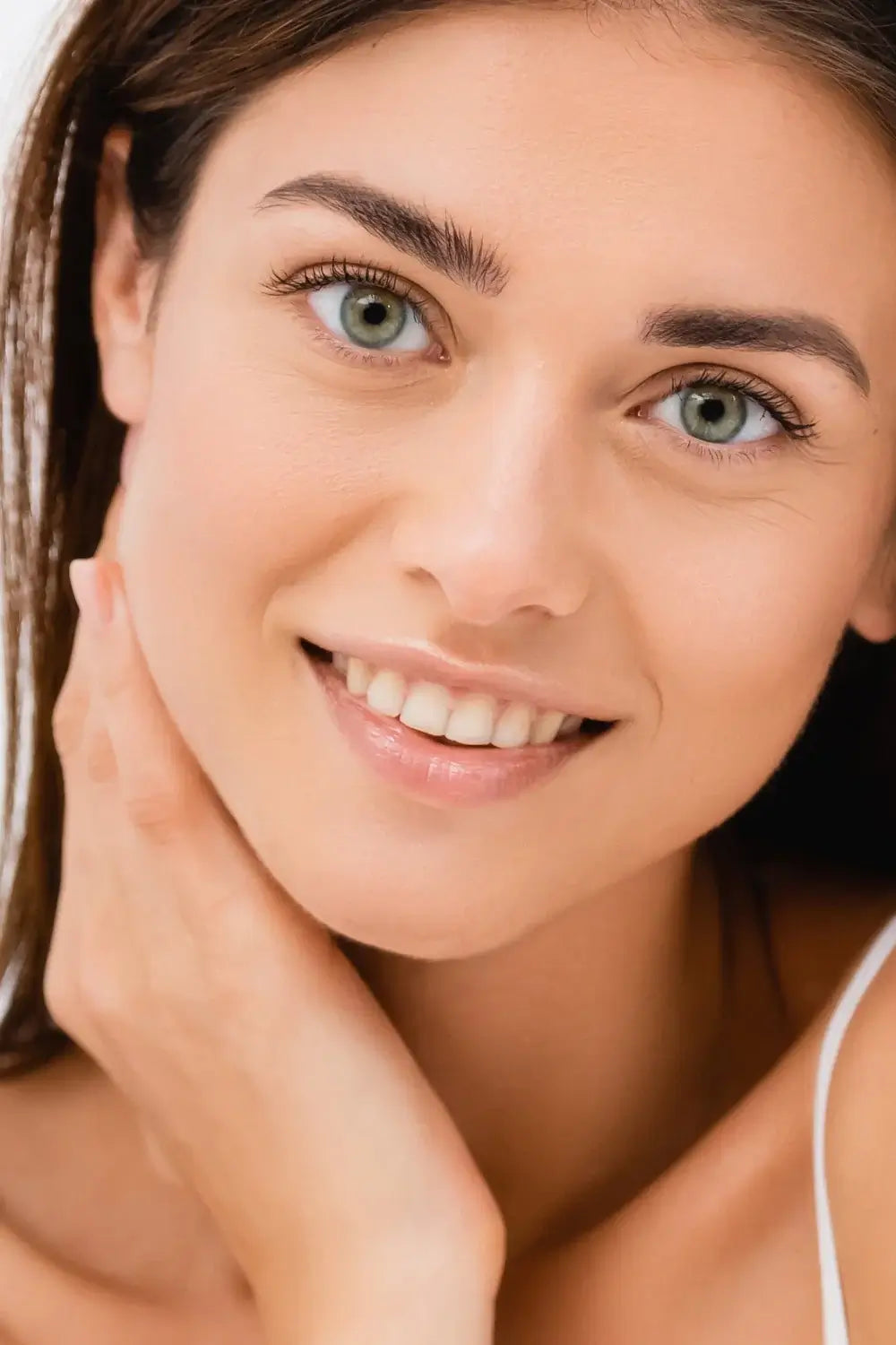 Frau mit entspanntem Lächeln, Hand am Hals – gepflegtes Erscheinungsbild