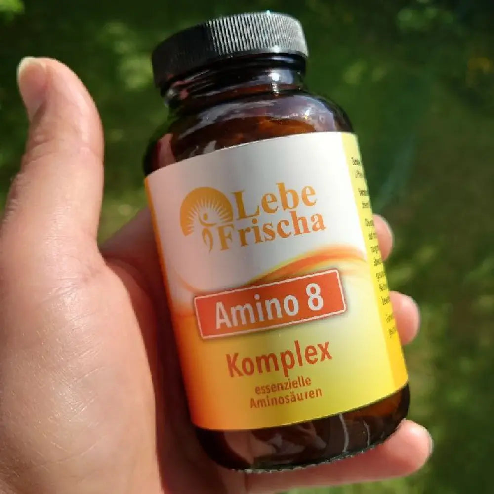Hand hält eine Amino 8 Komplex Flasche der Marke LebeFrischa vor grünen Rasen.