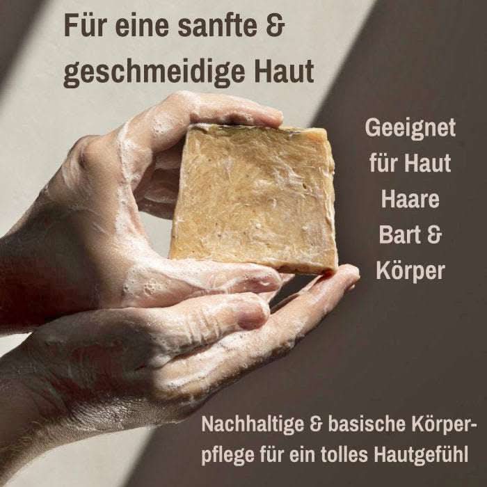 Zwei eingeseifte Hände halten eine Aleppo Seife; daneben sichtbare Texte „Für eine geschmeidige Haut“, „Geeignet für Haut, Haare, Bart & Körper“ sowie unten „Basische Körperpflege“.