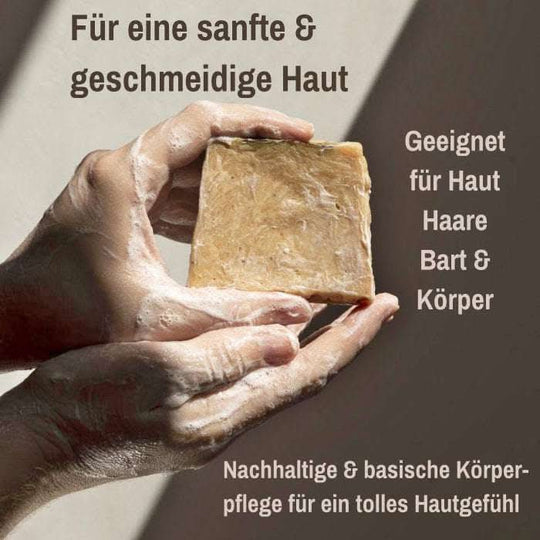 Zwei eingeseifte Hände halten eine Aleppo Seife; daneben sichtbare Texte „Für eine geschmeidige Haut“, „Geeignet für Haut, Haare, Bart & Körper“ sowie unten „Basische Körperpflege“.