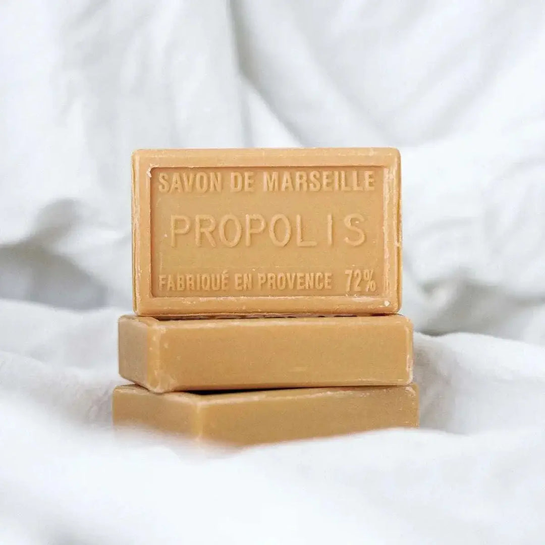 Mehrere Seifenblöcke auf weißem Handtuch mit dem sichtbaren Text „Savon de Marseille Propolis Fabriqué en Provence 72%“