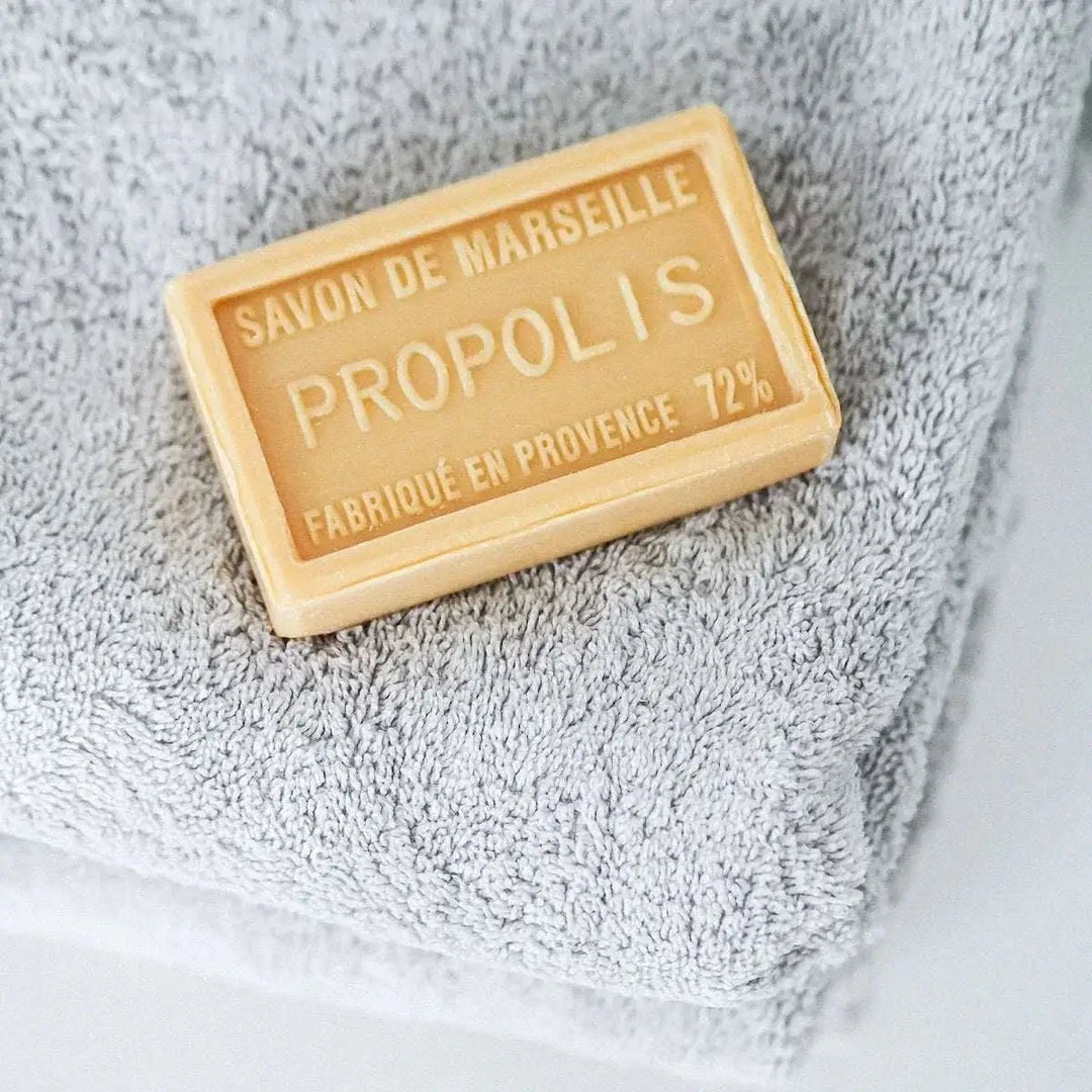 Seifenblock auf grauem Handtuch mit dem sichtbaren Text „Savon de Marseille Propolis Fabriqué en Provence 72%“