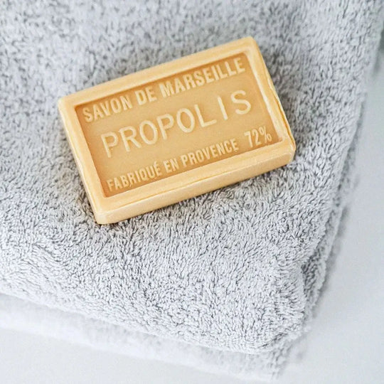 Seifenblock auf grauem Handtuch mit dem sichtbaren Text „Savon de Marseille Propolis Fabriqué en Provence 72%“